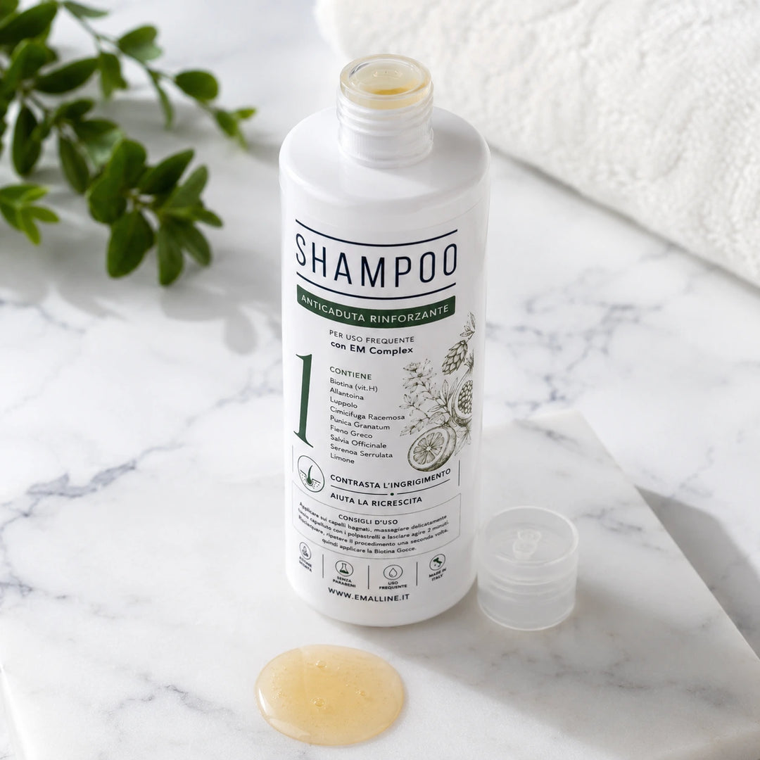 Flacone aperto di 331 Shampoo Rinforzante Coadiuvante Unisex su un piano di marmo bianco naturale con campionatura della texture fluida e dorata del prodotto.