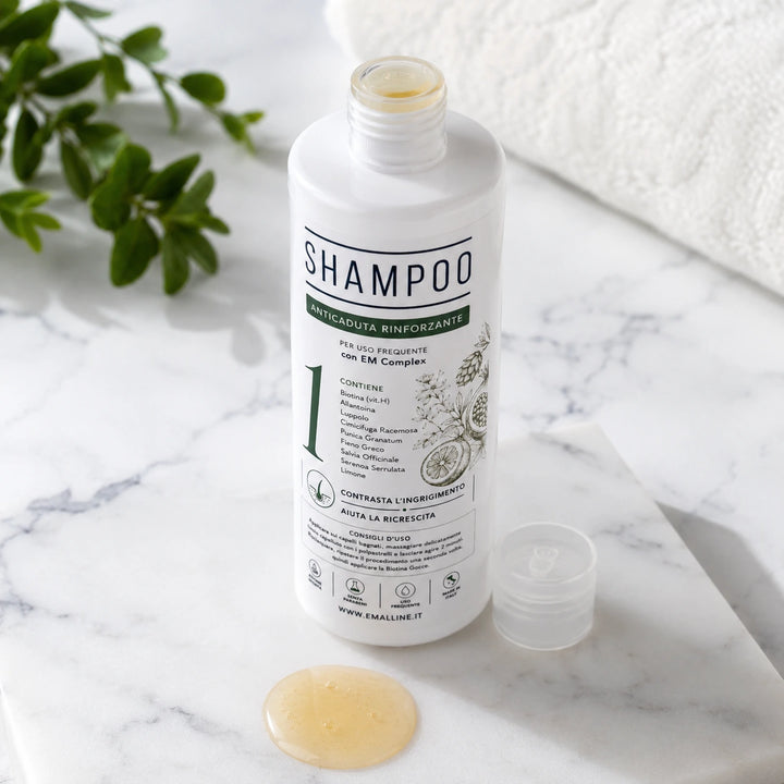 Flacone aperto di 331 Shampoo Rinforzante Coadiuvante Unisex su un piano di marmo bianco naturale con campionatura della texture fluida e dorata del prodotto.