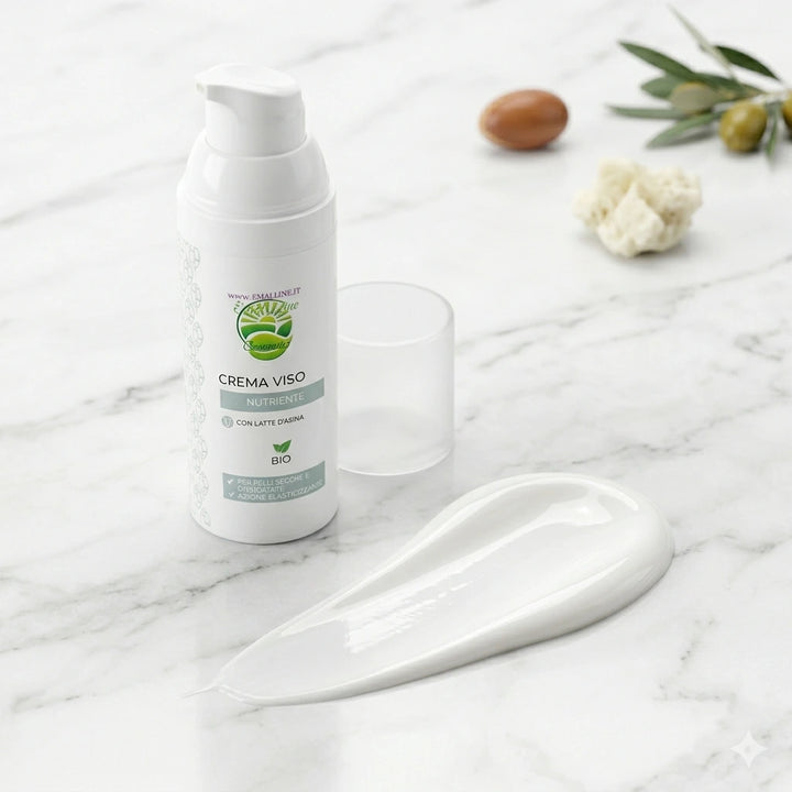 Dettaglio macro della texture ricca, solidamente bianca e semilucida della Crema Viso Nutriente EmalLine erogata in una scia fluida su piano di marmo, con flacone sullo sfondo.