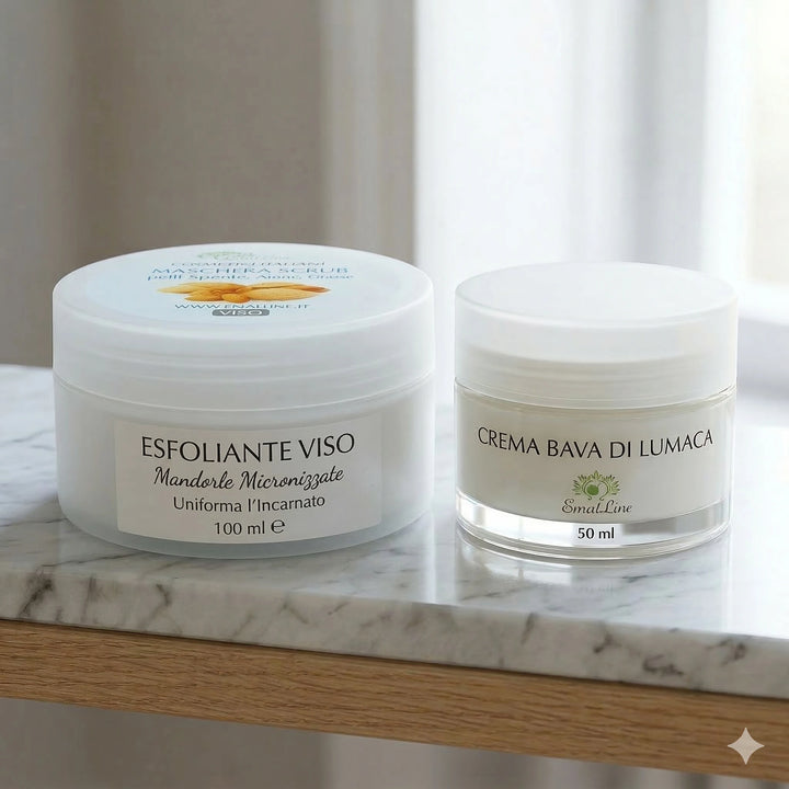 Kit Lumaca Perfect Skin Duo: scrub viso esfoliante alle mandorle da 100ml e crema viso alla bava di lumaca rigenerante da 50ml su piano in marmo